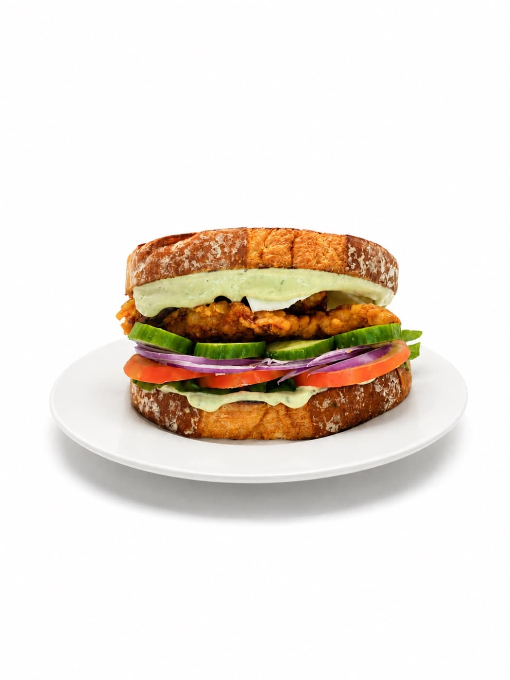 Sándwich de pollo empanizado servido en plato blanco